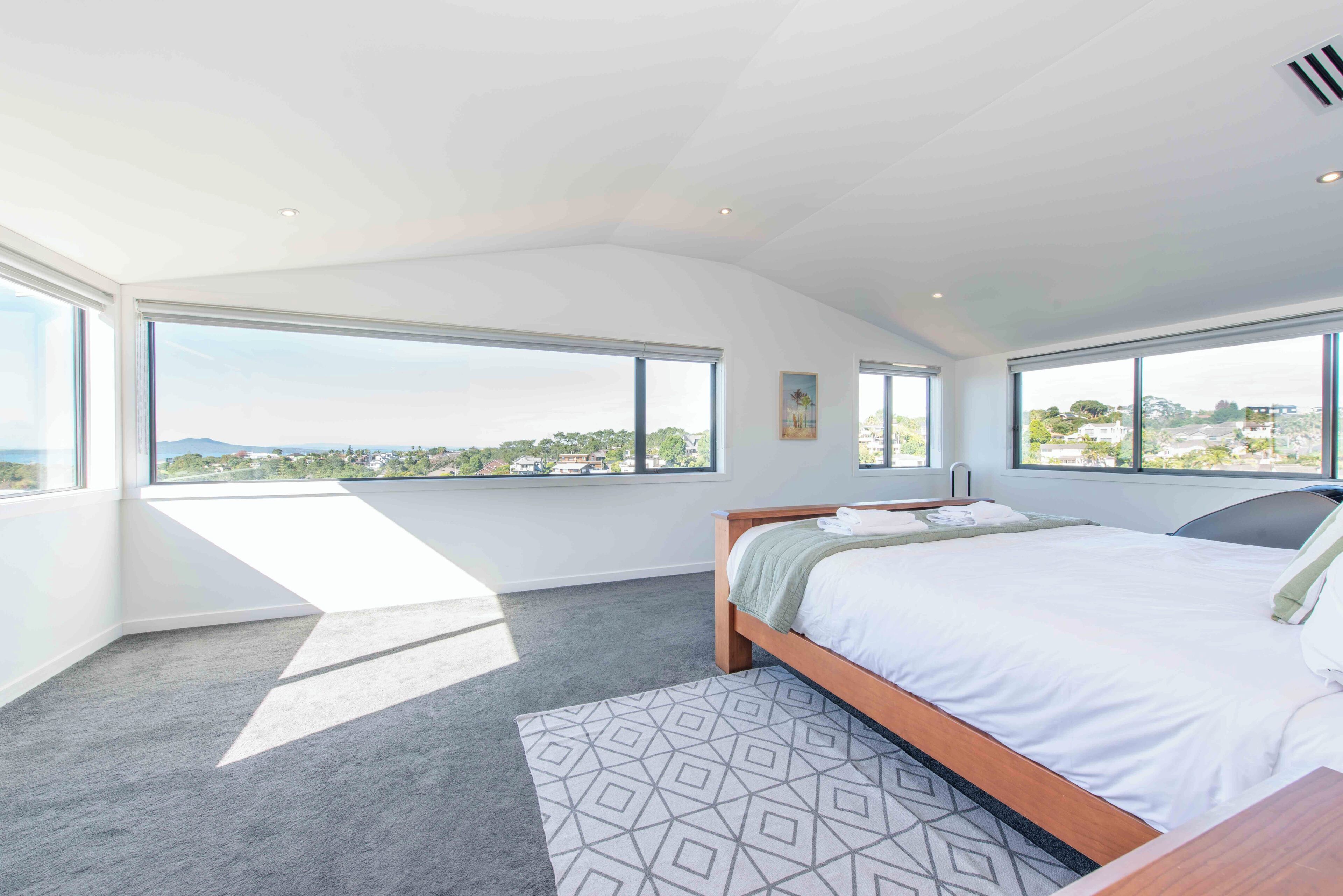 Una camera da letto con un letto grande, vista sulla città e un lucernario.