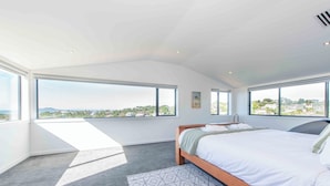 Une chambre avec un grand lit, une vue sur la ville et une fenêtre de toit.
