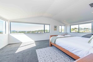 Une chambre avec un grand lit, une vue sur la ville et une fenêtre de toit.