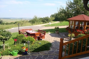 Eine Terrassenanlage mit Holztisch und -stühlen, einem Pavillon und einem Steinweg.