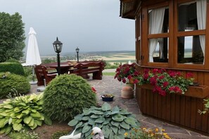 Ein Holzhaus mit einer Steinterrasse, einem Tisch mit Stühlen und einer Schwanstatue.