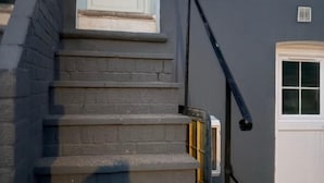 A set of exterior stairs leading to a door, a window, and a vent on the wall. - Spacious 5-bedroom Home in Chatham With Private Garden Sleeps 7 (Chatham)
