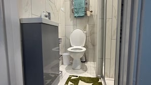 A bathroom with a white toilet, a towel rack with a blue towel, and a shower area. - Chatham 5-bed House, Sleeps 10 w/ Parking & Garden (Chatham)