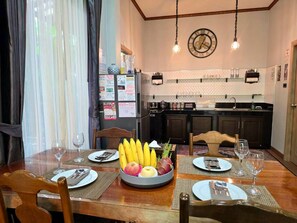 Una mesa de comedor lista con platos, cubiertos y un frutero.