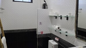 A bathroom with a toilet, sink, and shower area.