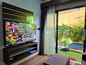 Una sala de estar con televisor, puerta corrediza al jardín y una mesita.