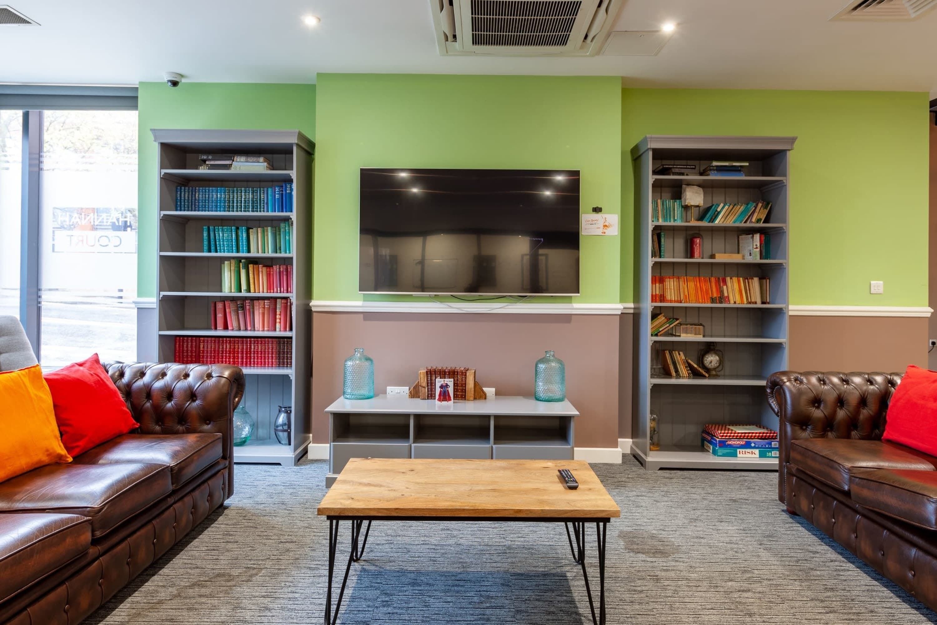 A cozy living room with leather sofas, a coffee table, and bookshelves filled with books.