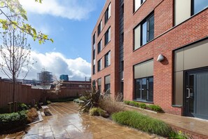 A modern brick building with multiple windows and a courtyard with a wet pavement. - Student Only Hannah Court (Sheffield)