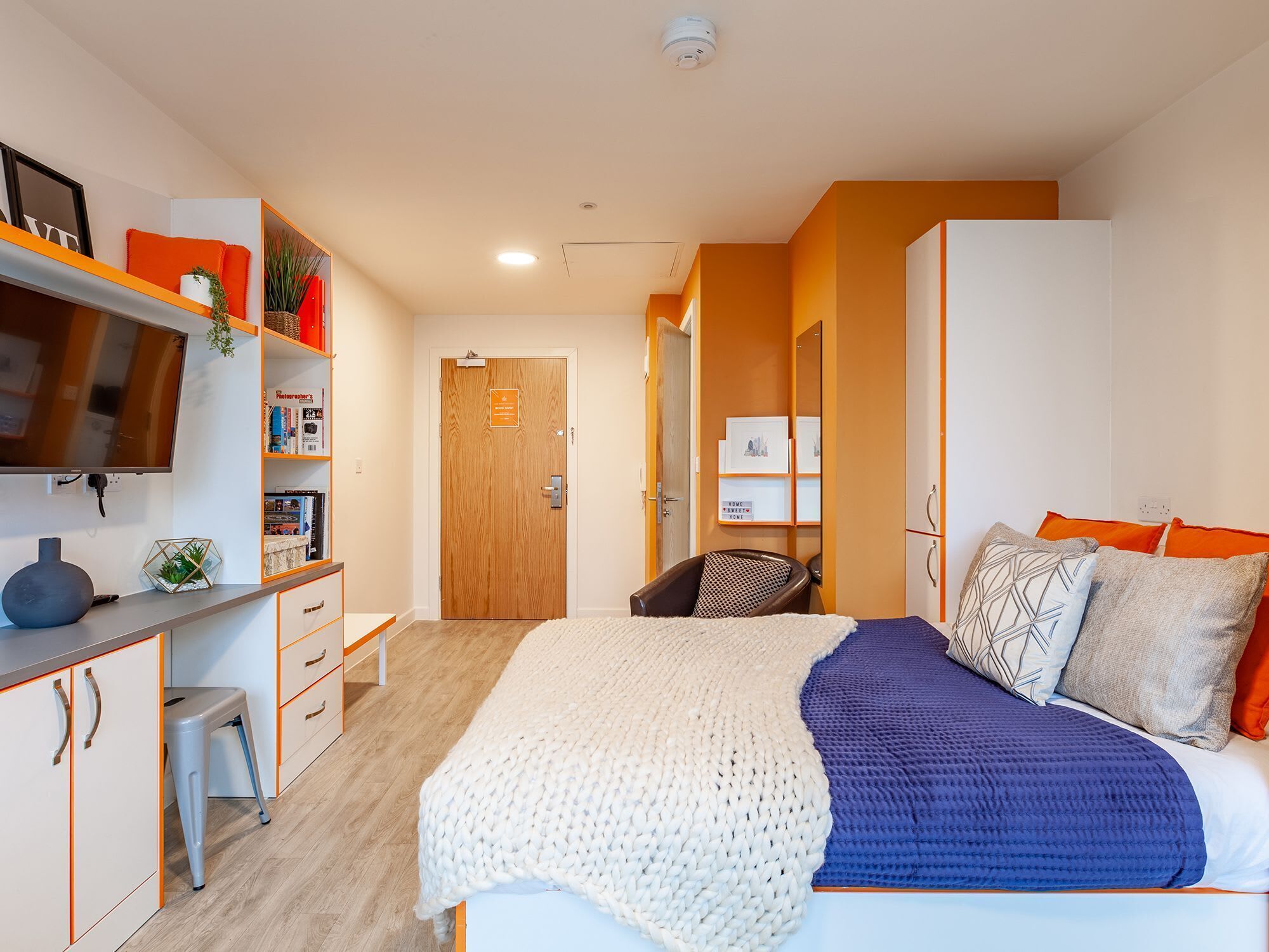 A bedroom with a bed, a desk, a chair, and a bookshelf.