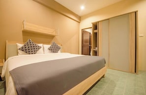 Una habitación de hotel con cama, armario y mesita de noche.