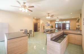 Una cucina moderna con isola centrale, elettrodomestici integrati e ventilatori a soffitto.