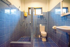 Un bagno con piastrelle blu, un WC, una doccia e un lavandino.