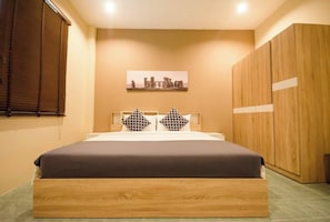 Ein Schlafzimmer mit einem Bett, einem Holzschrank, einem Fenster mit Jalousien und einem Wandbild.