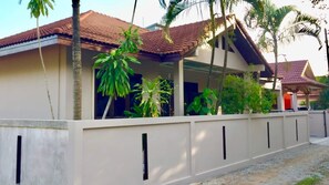 Un edificio residenziale con tetto in tegole, un portico coperto e una facciata esterna bianca con dettagli verticali neri.