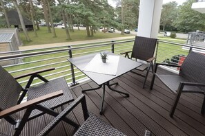 A covered outdoor seating area with a table and chairs, a railing, and a view of the surrounding area. - Holiday apartment with 2 bedrooms (Dierhagen)