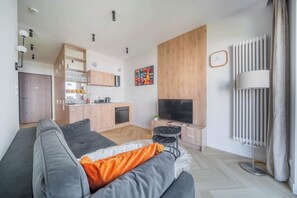 A modern living room with a sofa, a TV, and a kitchen in the background. - Kierbedzia Boutique Studio, Mokotów, Warsaw (Warszawa)