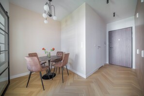 A dining area with a round table, four chairs, a vase with flowers, and a modern chandelier. - Kierbedzia Boutique Studio, Mokotów, Warsaw (Warszawa)
