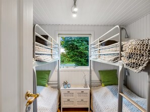 A bunk bed room with a window, a door with a brass handle, and a small table with decorative items. - "Alkmar" -  from the sea by Interhome (Hals)