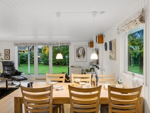 A dining area with a table set for four, surrounded by wooden chairs, with a view of a garden through glass doors. - "Alkmar" -  from the sea by Interhome (Hals)