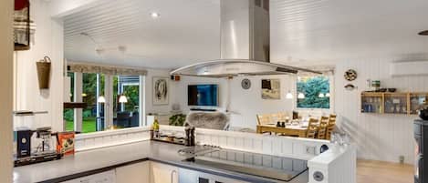 A modern kitchen with a central island, built-in oven, and a dining area with a view.