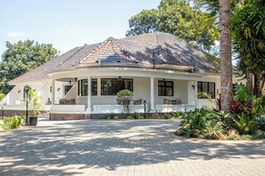 Et tosidet hus med tegltag, en overdækket veranda med siddepladser og en belagt indkørsel.