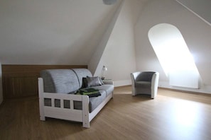 A room with a white sofa, a small chair, and a sloped ceiling. - Holiday home in Dranske with swimming pool (Dranske)