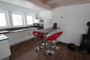 A kitchen with white cabinets, a black countertop, and red bar stools. - Holiday home in Dranske with swimming pool (Dranske)