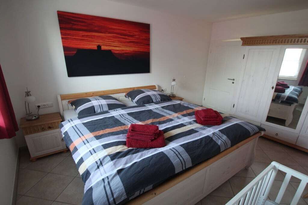 Ein Schlafzimmer mit einem Bett, einem Nachttisch, einem Schminktisch und einer Tür.