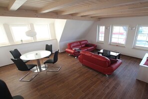 A modern living space with a dining area, red leather sofa, and large windows. - Holiday home in Dranske with swimming pool (Dranske)