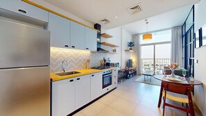 A modern kitchen with a built-in oven, a sink, and a dining area with a table and chairs. - Chic 1 Bed l Walking Distance to Dubai Hills Mall (Dubai)