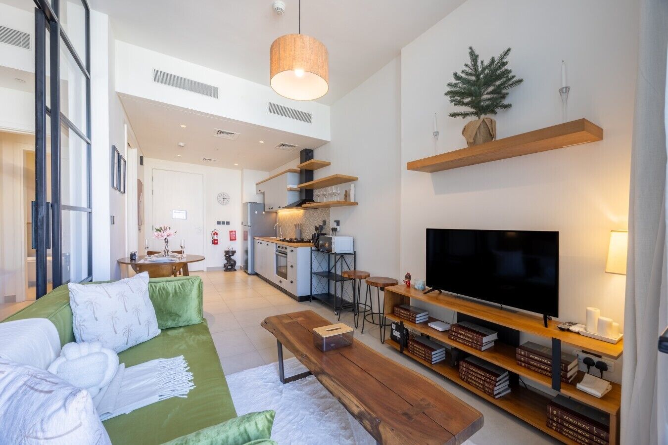 Un salon moderne avec un grand téléviseur à écran plat, un canapé vert et une table basse en bois.