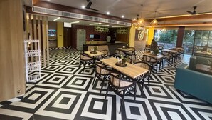 Un restaurante con suelo de patrón geométrico, varias mesas y sillas, ventiladores de techo y una zona de bar.