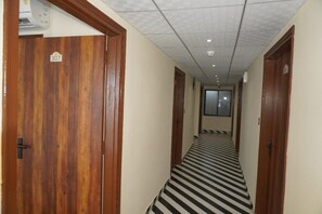 A hallway with wooden doors, a tiled floor, and a ceiling with recessed lighting. - Hotel Darbaar Inn (Jaipur)