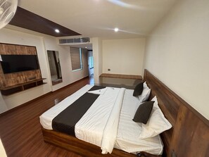 Un dormitorio con una cama grande, un televisor montado en un panel de madera y un ventilador de techo.