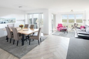 Ein modernes Interieur mit Essbereich, einer Sofagarnitur und Blick durch große Fenster.