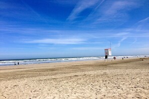 A beach with a lifeguard tower, sandy beach, and ocean waves. - Red Diver in House Bill15 (Juist)