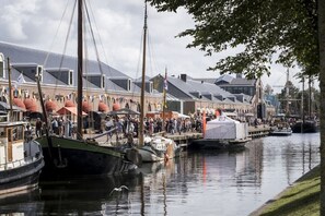 A marina with boats docked, a crowd of people, and buildings with sloped roofs. - Holiday home with 3 bedrooms (Julianadorp)