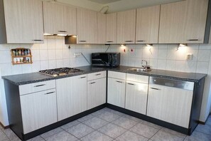 A kitchen with light wood cabinets, a gas stove, a microwave, and a dishwasher. - Holiday home with 3 bedrooms (Julianadorp)