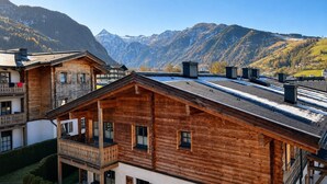 Eine Holzhütte mit einem Balkon vor einer Bergkulisse.