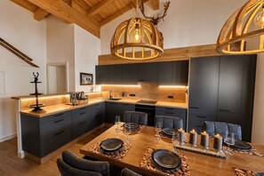 Cozinha moderna com armários escuros, ilha de madeira e iluminação pendente.