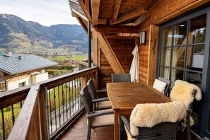 A wooden balcony with a table and chairs, overlooking a mountainous landscape. - Vrbo Property (Kaprun)