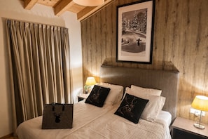 A hotel room with a large bed, wooden headboard, and a framed picture on the wall. - Vrbo Property (Kaprun)