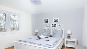 Quarto com cama, mesas de cabeceira e janela.