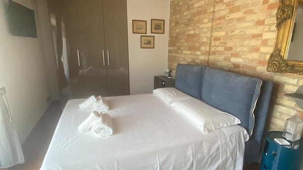 Une chambre d’hôtel avec un lit, une tête de lit bleue, un mur en briques et un plafond en bois.