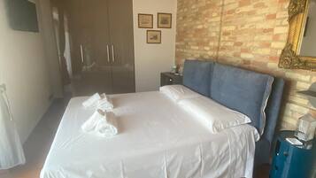 Une chambre d’hôtel avec un lit, une tête de lit bleue, un mur en briques et un plafond en bois.