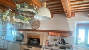 Une cuisine rustique avec une cheminée en briques, des poutres en bois et un luminaire suspendu.