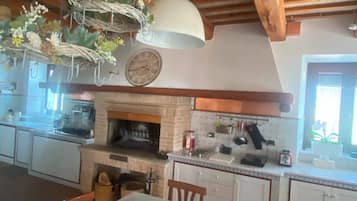Une cuisine rustique avec une cheminée en briques, des poutres en bois et un luminaire suspendu.