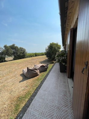 A pathway leading to a building with a view of a grassy field and trees. - Relais Infinito: Rooms and Views of the Marche Hills (Montefiore)