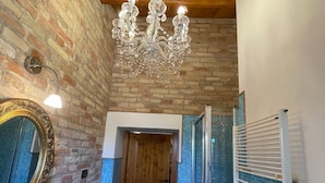 Une salle de bain avec un plafond en bois, un lustre, un miroir, un lavabo et un espace douche.