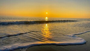 Une scène de plage avec des vagues et un coucher de soleil.